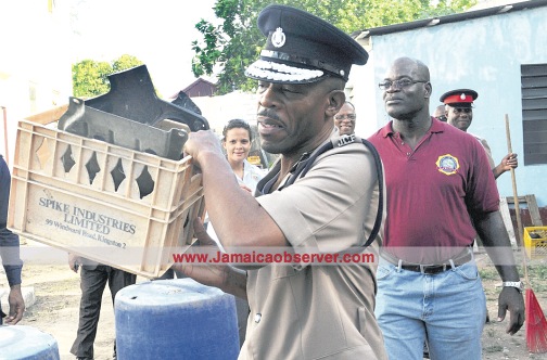 Police Commissioner Carl Williams carries a crate of debris as he leads a team of officers at the Half-Way-Tree Police Station on clean-up of the facility. (PHOTOS: GARFIELD ROBINSON)