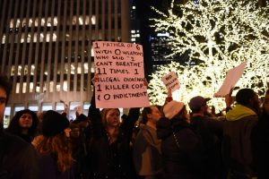 Protesters hold up signs across the street from Radio City Music Hall in a protest to a non indictment against a police officer in the death of Eric Garner, Wednesday Dec. 3, 2014, in New York. (David Handschuh/Yahoo News)