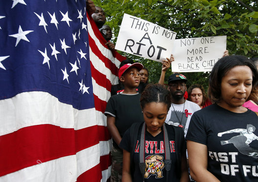 Jordan Johnson, left, 8, from Washington, Camille Chrysostom of Bowie, Md., and Jaimee Swift of Philadelphia, observe a moment of silence at Meridian Hill Park, also known as Malcom X Park, Thursday, Aug. 14, 2014 in Washington, to protest the fatal shooting of Michael Brown by police in Ferguson, Mo. Vigils were held across the country for people organizers say died at the hands of police brutality. (AP Photo/Alex Brandon)