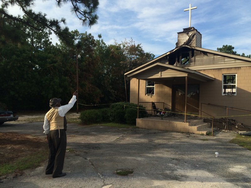 Pastor Bobby Jones points to the cross on top of Glover Grove Baptist Church in Warrenville, S.C., where he has preached for more than 30 years. The steeple was one of the only parts of the church left standing.