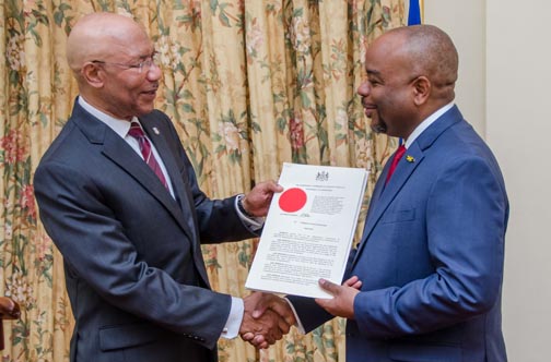 Governor-General, Sir Patrick Allen (left), presents the instrument of appointment to  Terrence Williams.