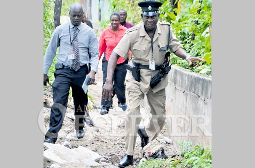 Police walk through the community of Mud Town yesterday after gunmen attacked and shot dead a pastor during a prayer meeting.