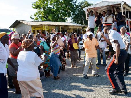 The Church and Corporal Marlando Gordon (right) engages residents of Prospect Crossing in song and dance. Occasion was a stop in the area during a peace march throughout ...