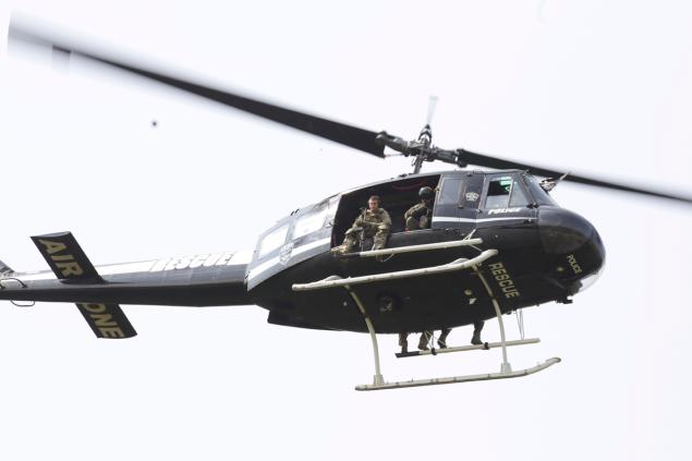 STACEY WESCOTT/AP A police helicopter patrols a swampy area near route 59 and Rollins in Fox Lake, Ill., where a manhunt is in progress after an officer was shot.  