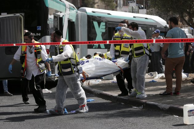 Israeli Zaka volunteers carry a body following a shooting attack on a bus in an east Jerusalem Jewish settlement adjacent to the Palestinian neighbourhood of Jabal Mukaber on October 13, 2015. Two attackers opened fire on a bus while another assailant carried out a car and knife assault in Jerusalem, leaving two people dead and five wounded in two separate incidents, Israeli authorities said. AFP PHOTO / THOMAS COEX        (Photo credit should read THOMAS COEX/AFP/Getty Images)