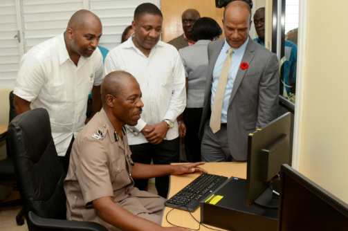 Commissioner of Police Dr Carl Williams (seated) tests out one of 10 computers in the new computer centre at the Jamaica Constabulary Force’s (JCF) Mobile Reserve. Looking on (from left) are: State Minister in the Science, Technology, Energy and Mining Ministry Julian Robinson; portfolio Minister Phillip Paulwell; and Minister of National Security Peter Bunting. (JIS Photo) 