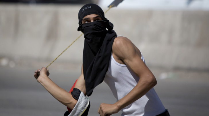 A Palestinian uses a sling shot to throw stones during clashes with Israeli troops at Qalandia checkpoint between Jerusalem and the West Bank city of Ramallah (AP photo