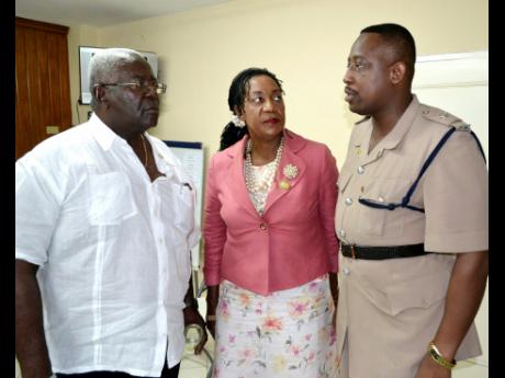 PHOTO BY CARL GILCHRIST Chairman of the St Ann Justices of the Peace Association, Pixley Irons (left) and Custos Norma Walters, pay keen attention to Superintendent Wayne Cameron, commander for St Ann, while the three discuss matters relating to policing in the parish.