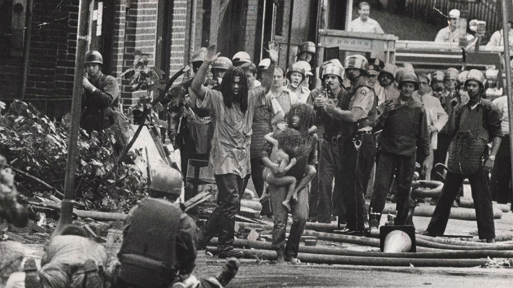In 1985, Philadelphia police dropped a bomb on a house occupied by a black group living communally called MOVE. Sixty-one homes were destroyed in the resulting fire, which gutted a city block. Although many writers have recounted the standoff that resulted in the death of 11 MOVE members, five of whom were children, it remains a faded memory in America’s recent history.(thegrio.com)